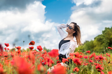 young woman in hat walk at poppy field pick flowers