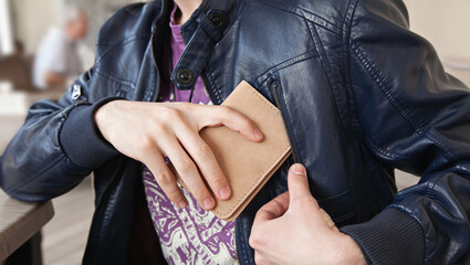 The man puts the leather wallet in the pocket of his jacket. Close-up, horizontal orientation, no face.