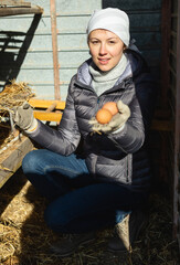 Young woman holding fresh eggs in a chicken coop. High quality photo