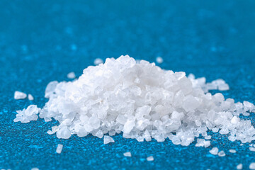 Coarse salt crystals on a blue table. sea salt. Background for advertising salty.