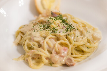 Italian pasta spaghetti Carbonara with fried bacon, parmesan cheese and parsley on white plate. Restaurant food concept
