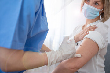 Doctor in personal protective suit inject vaccine shot to stimulating immunity of woman patient at risk of coronavirus infection. Coronavirus,covid-19 and vaccination concept