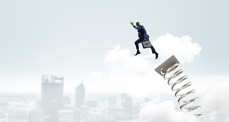 Businessman jumping on springboard . Mixed media