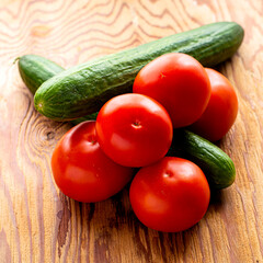two cucumbers and five tomatoes on a wooden background