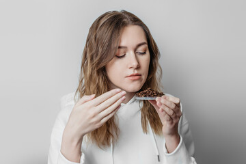 Loss of smell. Close up portrait of caucasian young woman sniffing coffee grains isolated on white background. Consequences of the coronavirus