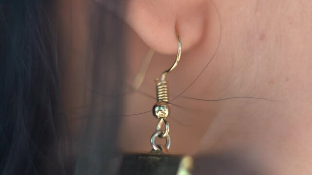 Close up view of a single earring hanging from the earlobe of a young woman, beauty, standards, luxury, modern, jewelry