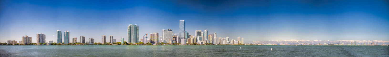 Panoramic view of Downtown Miami, Miami Beach Skyline and city port from Rickenbacker Causeway at sunset, with two airplanes in the sky