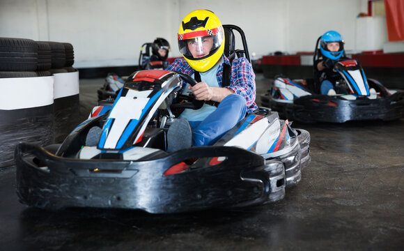Man driving racing car for karting in a circuit lap in sport club, people on background