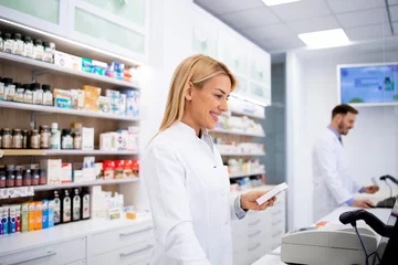 Muurstickers Female caucasian pharmacist selling medicines in pharmacy store. © littlewolf1989