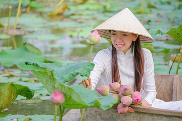 Vietnamese girl picking lotus flowers in pond