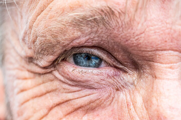 Close-up macro view on the blue eye of senior man smiling - 430087768