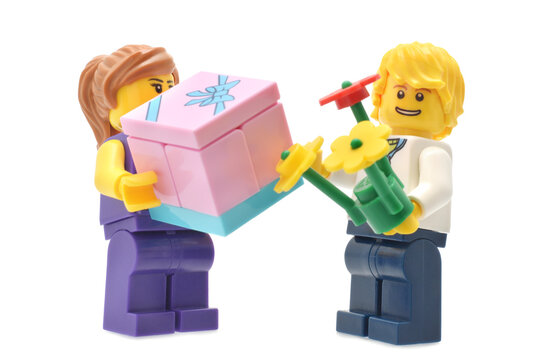 Lego minifigures boy and girl with flowers and gift isolated on white. Editorial illustrative image of birthday.