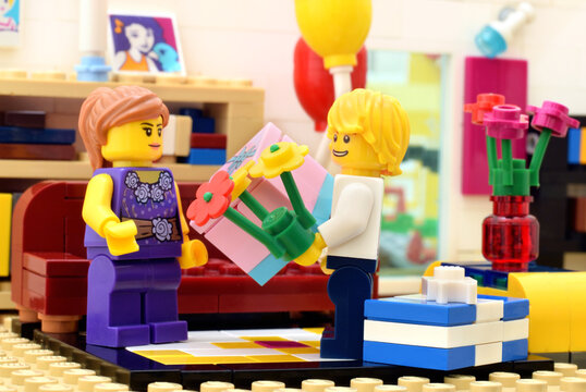 Lego minifigures boy and girl with flowers and gift in room. Editorial illustrative image of birthday.