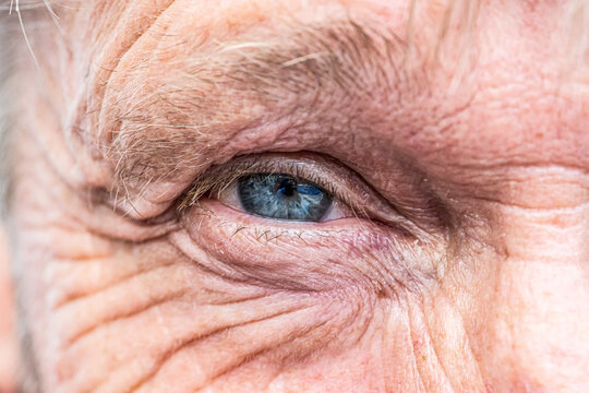 Close-up macro view on the blue eye of senior man smiling