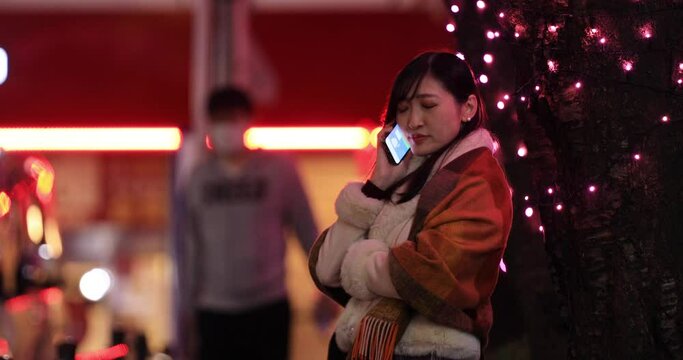 A Japanese woman calling phone at the illuminated street