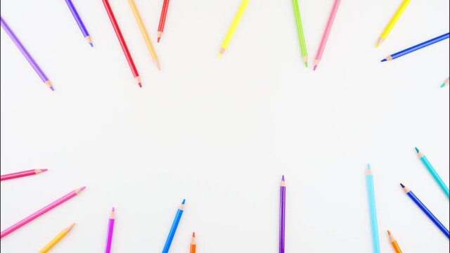 Colored pencils disappear on white desk. Stop motion