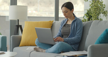Woman sitting on the couch and working with her laptop