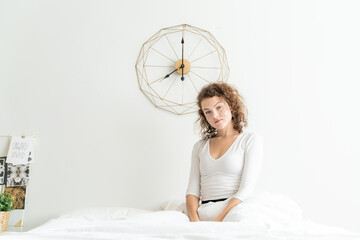 Beautiful women wake up on white bed in morning with watch on background