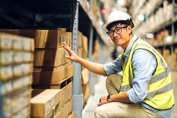 Portrait of smiling asian engineer man order details checking goods and supplies on shelves with...