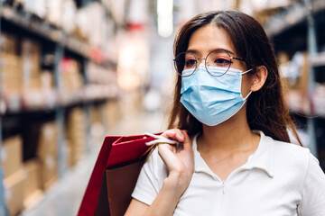 Young beautiful asian woman in quarantine for coronavirus wearing surgical mask face protection with social distancing shopping at store.covid19 and new normal concept