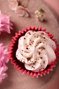 Red Velvet Cupcake On A Gray Plate, Near Sakura And Apricot Flowers, On A Pink Background, Top View.