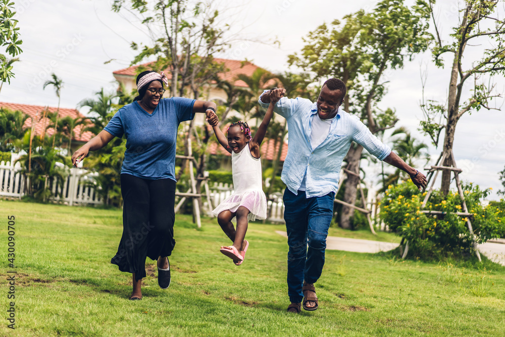 Wall mural Portrait of enjoy happy love black family african american father and mother with little african girl child smiling and play having fun moments good time in summer park at home