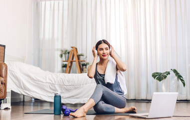 Portrait of sport asian woman in sportswear sitting relax and practicing yoga and do fitness exercise with laptop computer in bedroom at home.Diet concept.Fitness and healthy lifestyle