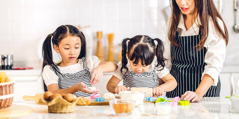 Portrait of enjoy happy love asian family mother and little toddler asian girl daughter child having fun cooking together with dough for homemade bake cookie and cake ingredient on table in kitchen