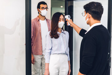 Group of professional asian business and using infrared thermometer for checking body temperature...