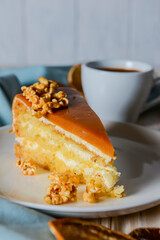 One piece of Caramel cake with pop corn on top served on a white plate. Dried oranges and a cup of Espresso coffee.