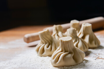 Georgian dumplings Khinkali with meat, on a wooden board with flour, black background.