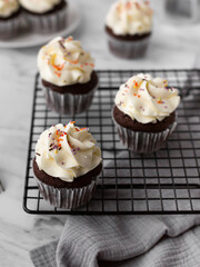 Chocolate cupcakes on a black metal grill on a light background with a coffee pot