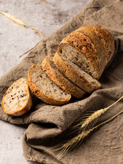 Sliced bread in burlap. Next to it are ears of wheat.