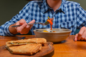 Young man eating salad in restaurant or diner. Georgian cuisine restaurant concept. Vegetable salad with lavash roll.