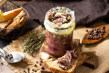 Beef stew in a glass jar on a brown wooden table close-up in rustic style