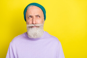 Photo of unsure cute age gentleman wear violet sweater headwear looking empty space isolated yellow color background