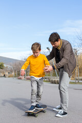 Fototapeta premium Father is teaching his son to ride a skateboard, outdoors