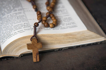 Wooden rosary and open Bible in the background