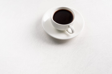 White ceramic cup with coffee on a white table Minimalism.