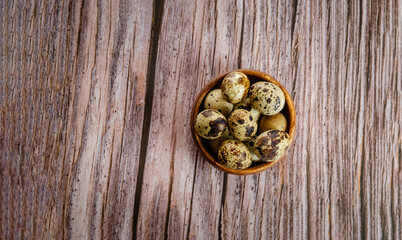 Obraz na płótnie Canvas Quail eggs in a wooden bowl on a wooden background. Sweets. Easter