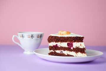 A piece of chocolate cake with vanilla cream. Berries inside and a piece of tangerine on top.