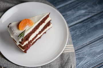 A piece of chocolate cake with vanilla cream. Berries inside and a piece of tangerine on top.
