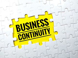 Selective focus.Word BUSINESS CONTINUITY with jigsaw puzzle on yellow background.Business concept.