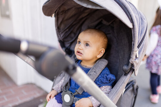 Adorably baby looking up in gray stroller on the sidewalk