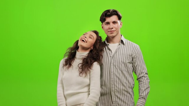A man and a woman are standing and looking at the camera. They are happy and smile. They are standing on a green background. Green screen. 4K