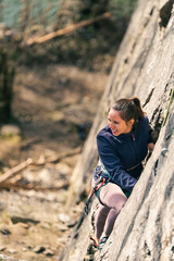 Young happy female climber looks at the landscape from a climbing route.