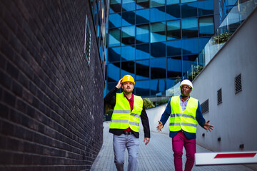 Engineer discussing the structure of the building with architects colleague at construction site. Having a problem.