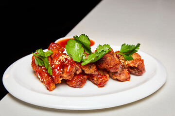 Sesame fried chicken wings with sauce and parsley. Close-up, selective focus.