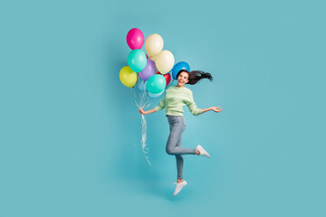 Fototapeta na wymiar Full size photo of young happy cheerful excited girl jumping with balloons in hand isolated on blue color background