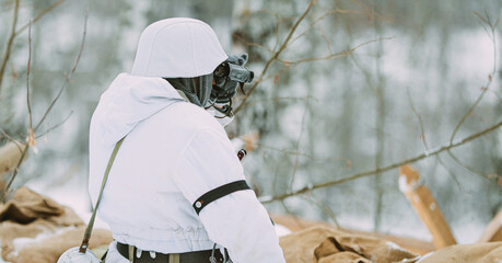 German Wehrmacht Infantry Soldier In World War II Soldiers Sitting In Ambush In Winter Forest And Looking At Old Army Binoculars. Historical Re-enactment. WWII. Winter Snowy Day
